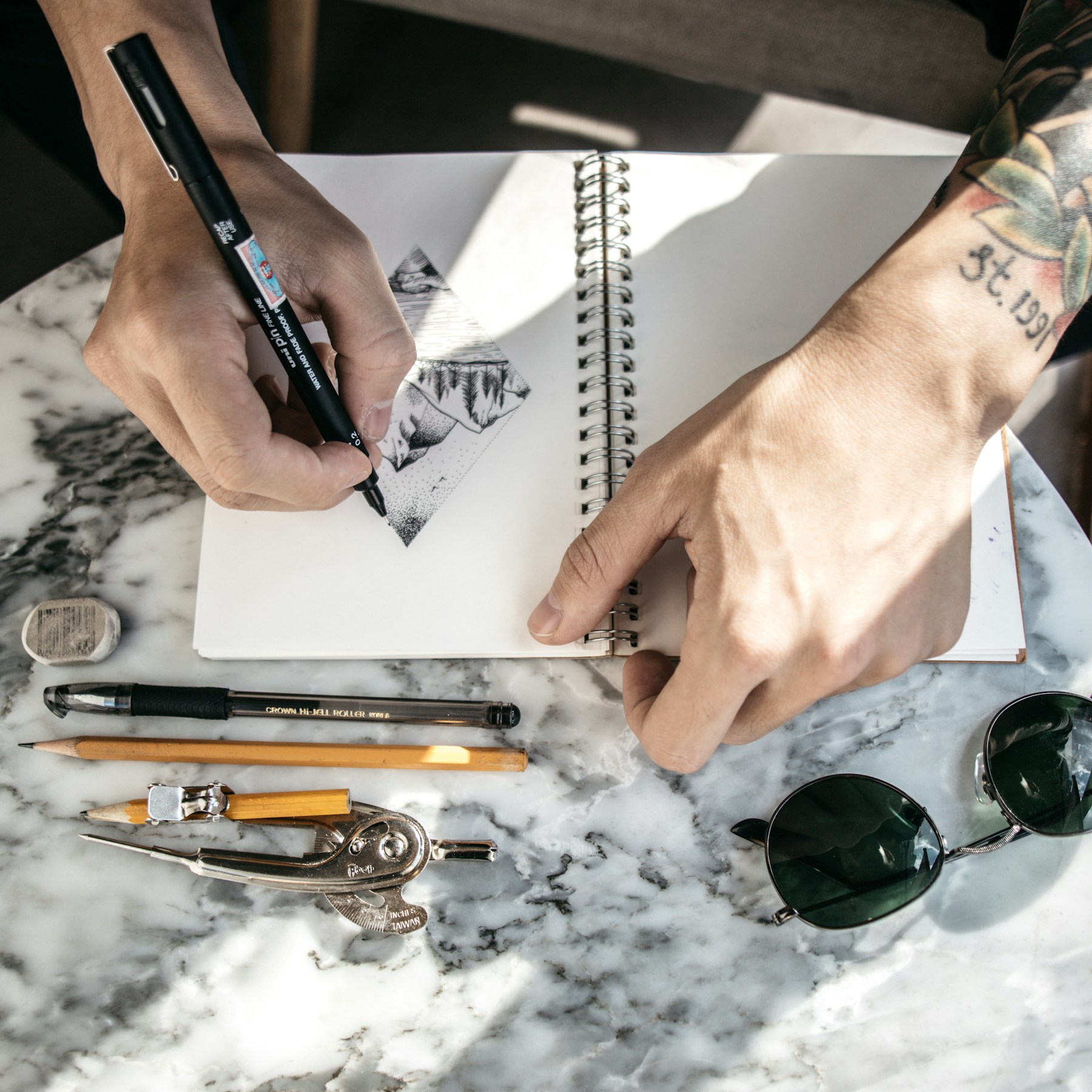 A person sketching a design in a notebook with a pen